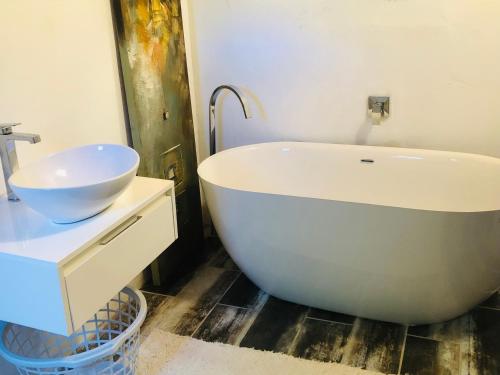 Un baño con una gran bañera blanca y un lavabo. en 31 on Kloof, en Aurora