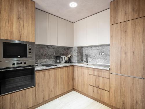 a kitchen with wooden cabinets and a microwave at The Boulevard Luxury Apartment in Sofia
