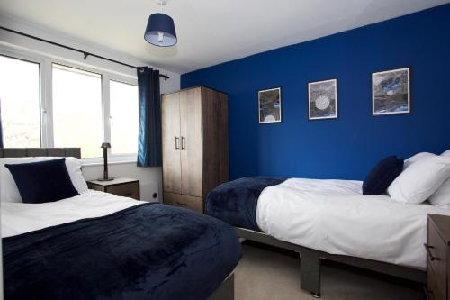 two beds in a room with blue walls at GERARD WALK - Spacious Home, High Speed Wi-Fi, Free Parking, Garden in Swindon
