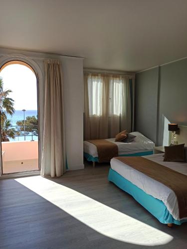 une chambre avec deux lits et une grande fenêtre dans l'établissement Hotel Restaurant Miramar L'orchidée, à La Ciotat