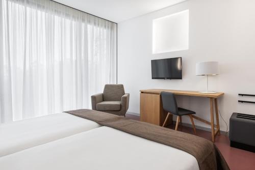 a hotel room with a bed and a desk and a chair at Pousada Meaño in Meaño