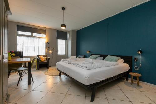 - une chambre avec un grand lit et un mur bleu dans l'établissement Studio Kon. Emmaweg 6, Vrouwenpolder, à Vrouwenpolder