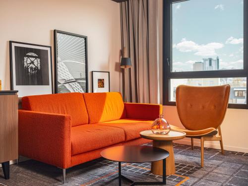 an orange couch in a living room with a window at Novotel Paris Vaugirard Montparnasse in Paris