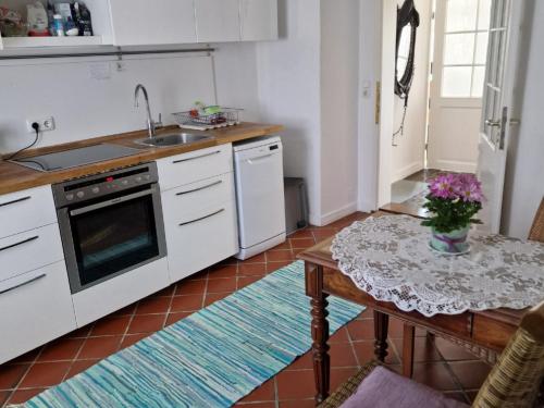 una cocina con armarios blancos y una mesa con flores. en Ferienwohnungen Heinrichsberger en Bad Aibling