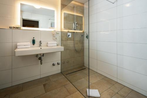 a bathroom with a shower, sink, and mirror at Hotel Schwabenwirt in Berchtesgaden