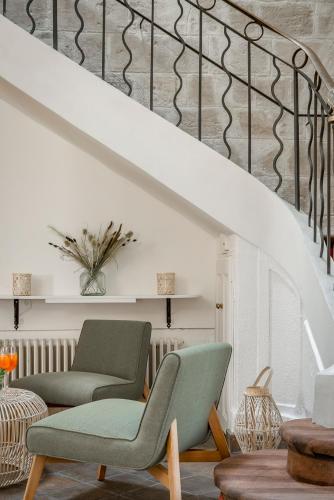 a living room with a green chair and stairs at Hôtel la Magnaneraie in Villeneuve-lès-Avignon