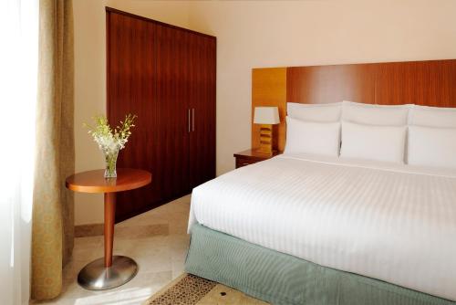 a bedroom with a white bed and a wooden headboard at Wyndham Garden Salalah Mirbat in Salalah