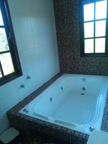 a bath tub in a bathroom with a window at Cobertura centro Ibitpoca MG in Lima Duarte
