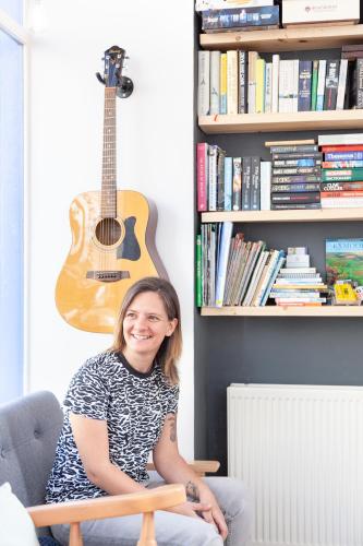a woman sitting in a chair with a guitar on the wall at Ocean Backpackers self-catering hostel in Ilfracombe