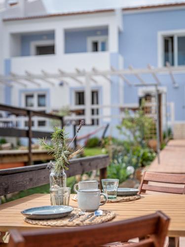 a wooden table with plates and drinks on a balcony at Ocean House Alentejo in Porto Covo