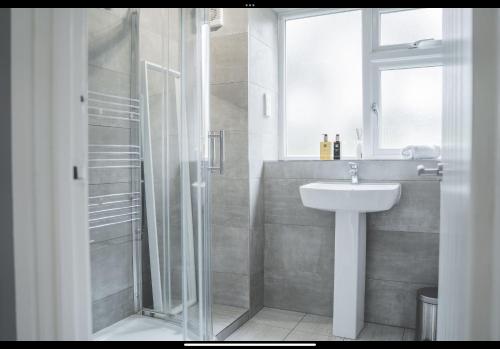 a white bathroom with a sink and a shower at The Whetstone in Birmingham