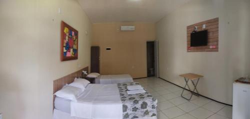 a bedroom with two beds and a tv on the wall at Pousada Itarema Residence in Itarema