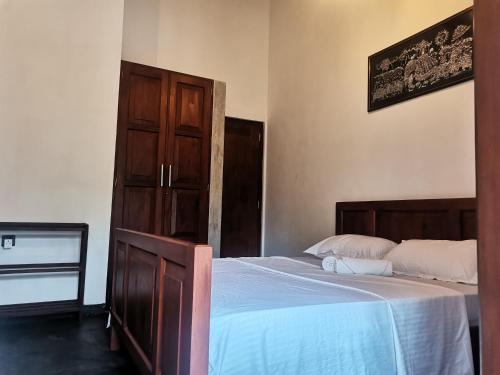 a bedroom with a bed and a wooden cabinet at Nilupul Villa in Ambalangoda