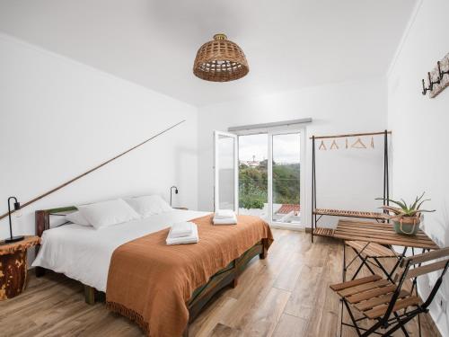 een witte slaapkamer met een bed en een raam bij Ocean House Alentejo in Porto Covo