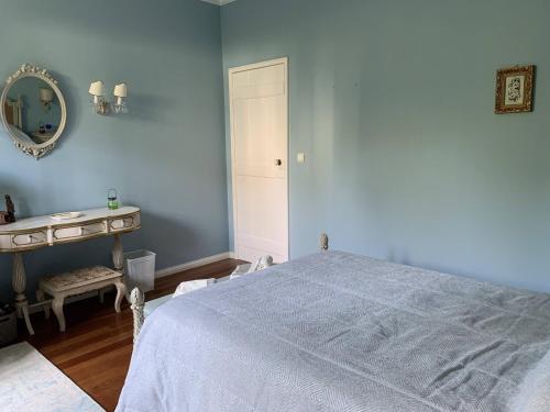 Dormitorio azul con cama y espejo en Casa Delft en Furnas