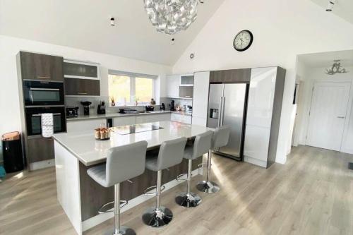 a kitchen with a large island with chairs and a clock at Camden House luxury home near Ben Nevis Scotland Highlands in Fort William