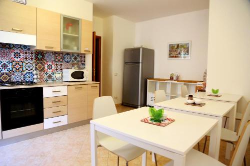 eine Küche mit einem weißen Tisch und Stühlen sowie einem Kühlschrank in der Unterkunft B&B Siciliò in Santa Flavia