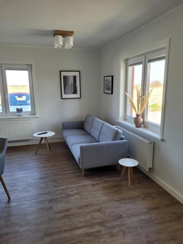 a living room with a blue couch and two tables at Apartment Südwesthörn in Emmelsbüll-Horsbüll