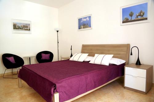 a bedroom with a bed with purple sheets and two chairs at B&B Siciliò in Santa Flavia