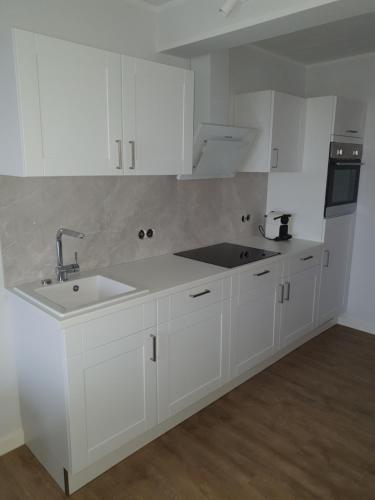 a kitchen with white cabinets and a sink at Apartment Südwesthörn in Emmelsbüll-Horsbüll