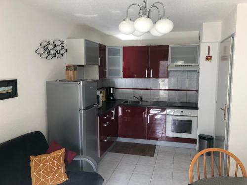 eine Küche mit Edelstahlgeräten und roten Schränken in der Unterkunft Appartement cosy 100m plage de Pentrez in Saint-Nic