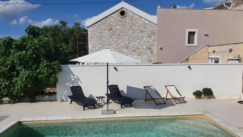 patio z krzesłami i parasolem przy basenie w obiekcie Vacation home Villa Santa Eufemia w mieście Sutomišćica