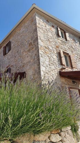 a brick building with some tall grass in front of it at Vacation home Villa Santa Eufemia in Sutomišćica
