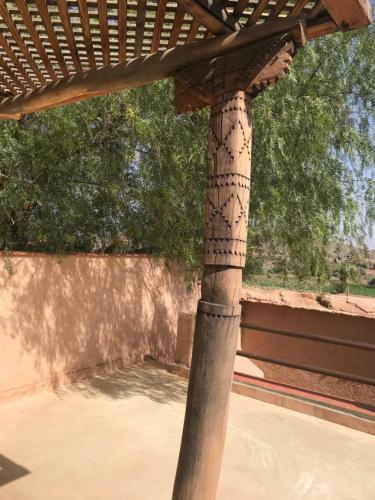 a wooden pergola with a view of a tree at Côté Sud in Ouarzazate