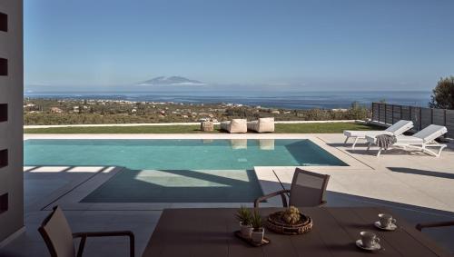 una piscina con tavolo, sedie e oceano di Julieta Villas a Città di Zante