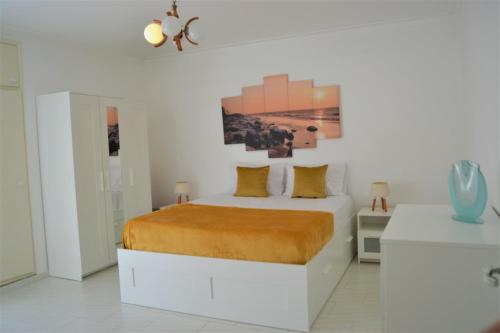 um quarto branco com uma cama e um quadro na parede em Apartamento espaçoso com estacionamento incluído em Portimão