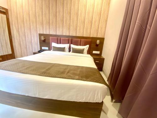 a bedroom with a large bed with brown curtains at Hotel Mumbai House-LIG Behind CHL Hospital in Indore