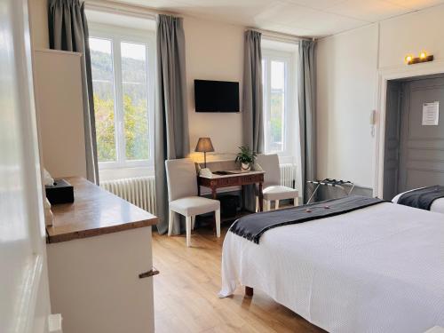 Cette chambre comprend un lit, un bureau et une table. dans l'établissement Hôtel Restaurant La Désirade, à Saint-Désirat