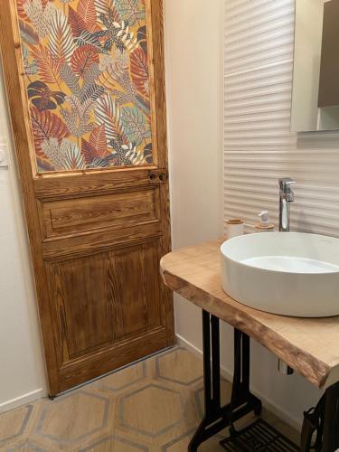 baño con lavabo blanco y puerta de madera en Escapade Courseullaise, en Courseulles-sur-Mer