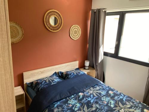 1 dormitorio con cama con sábanas azules y ventana en Escapade Courseullaise, en Courseulles-sur-Mer