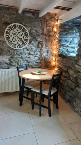 a table and chairs in a room with a stone wall at Merrion Cottage Penmachno Betws y Coed Conwy in Penmachno