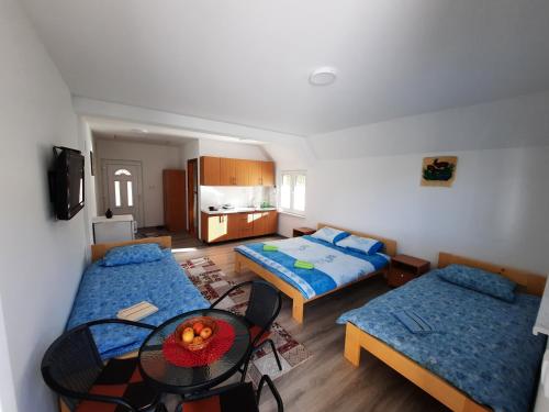 a room with three beds and a table in it at Apartmani Vila na Drini in Foča