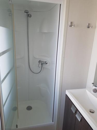 une douche avec une porte vitrée à côté d'un lavabo dans l'établissement Mobil Home Camping des 7 Fonts, à Agde