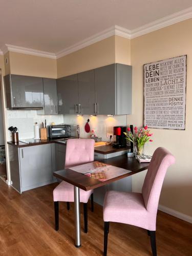 a kitchen with a table and two pink chairs at Strandappartement 715 im Plaza Premium Hotel in Timmendorfer Strand