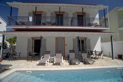 a villa with a swimming pool in front of a house at Nicola's Apartments in Kassiopi