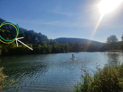 a man is standing on a boat on a lake at Haus Adler - Komplettes Ferienhaus am Badesee in Erzgrube