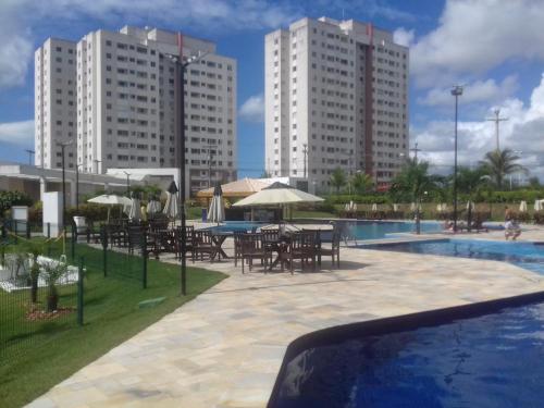 a pool with tables and umbrellas next to tall buildings at Piatã apartamento com Clube in Salvador