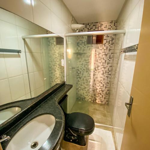 a bathroom with a shower and a toilet and a sink at Aruanã Chalés in Japaratinga