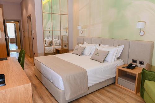 a bedroom with a large bed with white sheets and pillows at White Hill Hotel, SPA & Conferences in Durrës