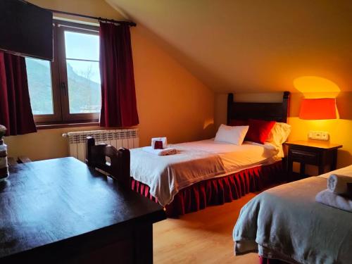 um quarto com 2 camas e uma janela em Hotel Cumbres de Valdeón em Posada de Valdeón