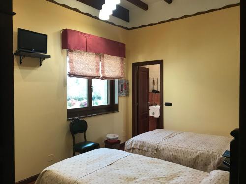 a bedroom with two beds and a tv and a window at Hotel Batán in Villalba