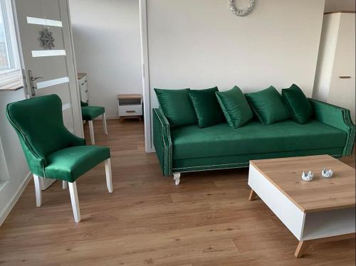 シュチェチンにあるMieszkanie Centrumのリビングルーム(緑のソファ、テーブル付)