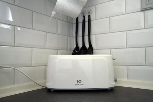 a toaster with two utensils on top of it at Nicola's Apartments in Kassiopi