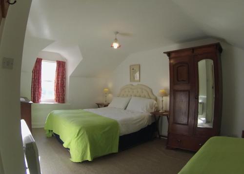 a bedroom with a bed with a green blanket at Wood House Cottage in Cockermouth