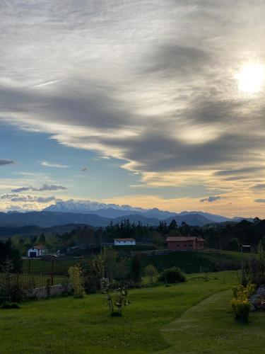 a cloudy sky over a field with mountains in the background at La buganvilla en Udias alojamiento in Comillas