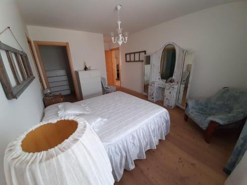 1 dormitorio con 1 cama blanca y 1 silla en casa Rosalba, en Strigno